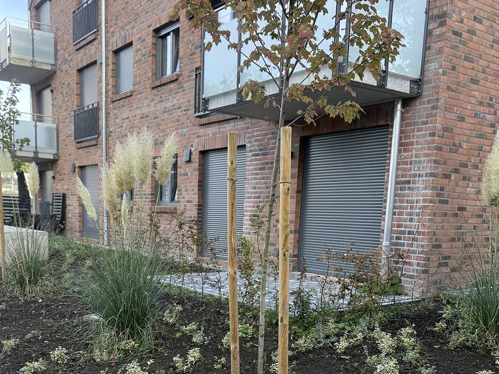 Klinkergebäude mit gepflegten Beeten und gepflastertem Weg